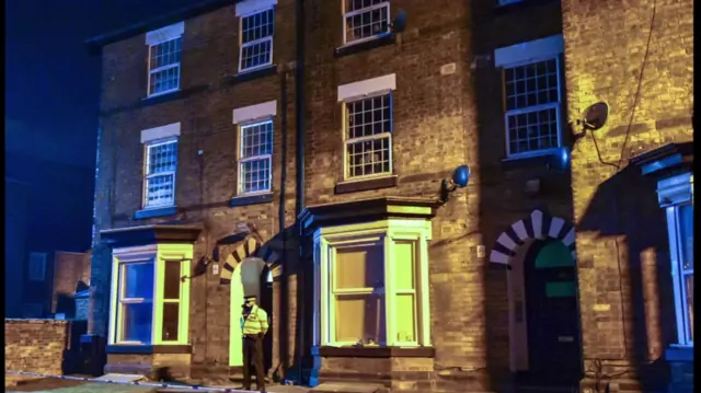 A policeman stands guard outside an address being seached