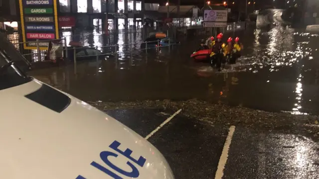 A police van with firefighters in the background