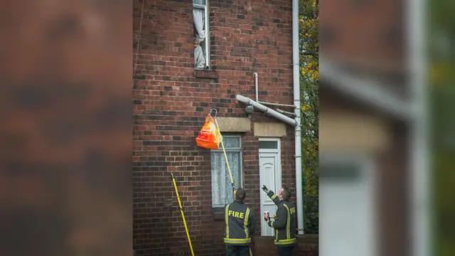 Firefighters lift a bag to a woman