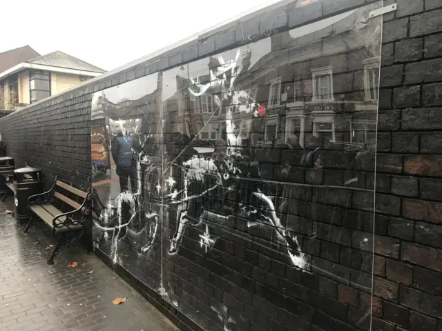 The defaced mural, protected by plastic sheet