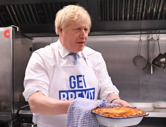 Boris Johnson holds a pie