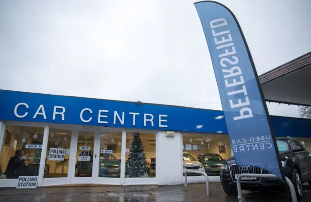 A Christmas tree stands in the window of Petersfield Used Car Centre in Hampshire, which is being used as a polling station