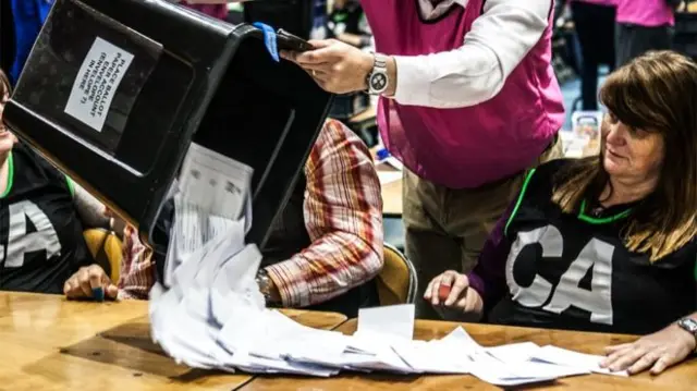 Ballot boxes are emptied on to tables and the number of papers are counted