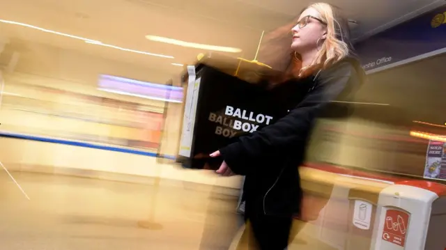 A woman carrying a ballot box