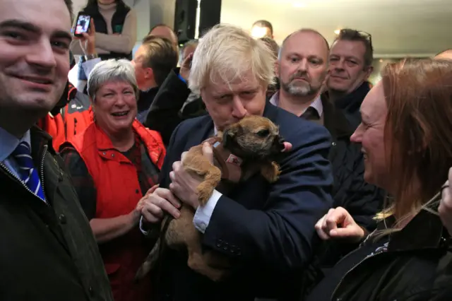 Boris Johnson kisses a supporter"s dog during a visit to see newly elected Conservative party MP in Sedgefield