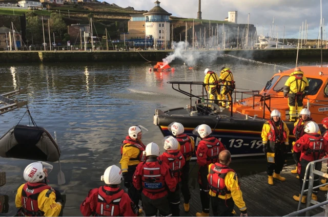 Lifeboat crews with smke flare in dinghy