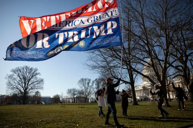 A man waving a flag saying "Veterans for Trump" outside the Capitol building