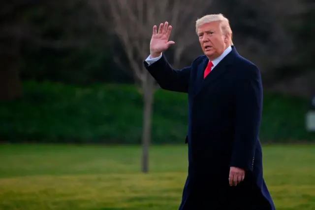 Donald Trump waves as he walks across the White House lawn