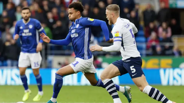 Josh Murphy of Cardiff City moves the ball forward while closely marked by Tom Clarke of Preston