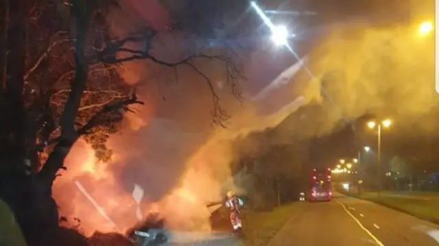 Firefighter next to burning car