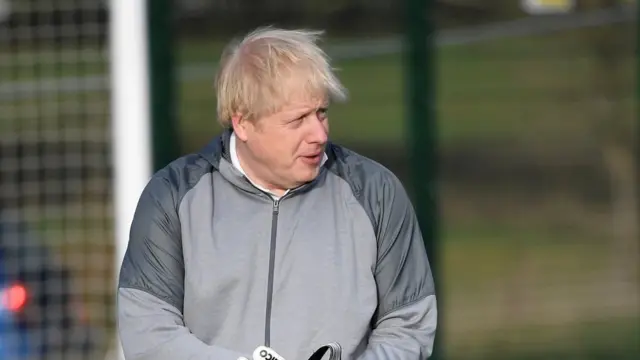 British Prime Minister Boris Johnson puts on goalkeeping gloves before a girls' football match during an election campaign event on December 7, 2019 in Cheadle Hulme, United Kingdom