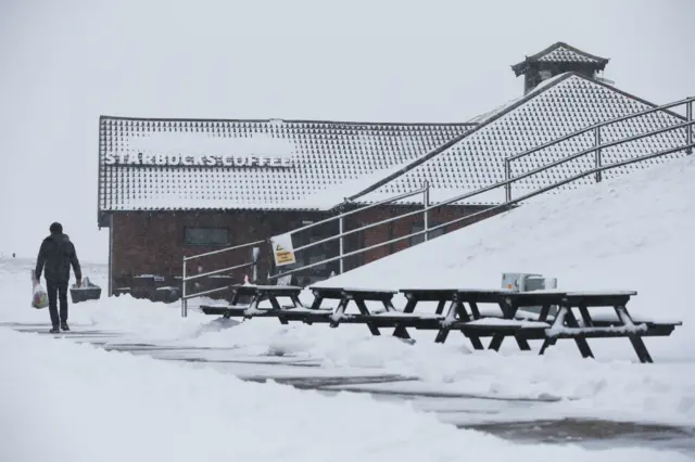 A man walks past the Starbucks Coffee store at the Membury Services on the M4,