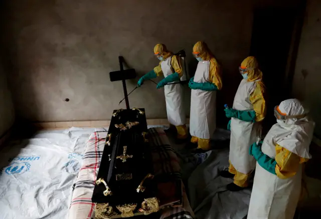 A healthcare worker sprays a room during a funeral of Kavugho Cindi Dorcas who is suspected of dying of Ebola in Beni, North Kivu Province of Democratic Republic of Congo