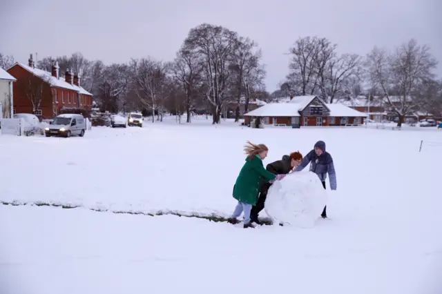 Children push a giant ball of snow over the cricket pitch in Hartley Wintney, in Hampshire, 40 miles west of London