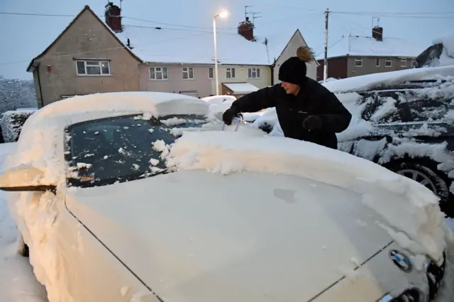 A motorist clears the windows of a vehicle in Bristol after snowfalls yesterday and overnight were expected to bring widespread disruption