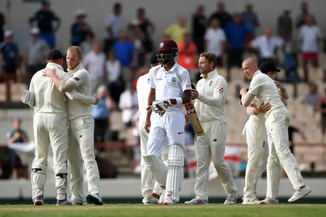 The England players celebrate victory as Roston Chase of the West Indies leaves the field not out