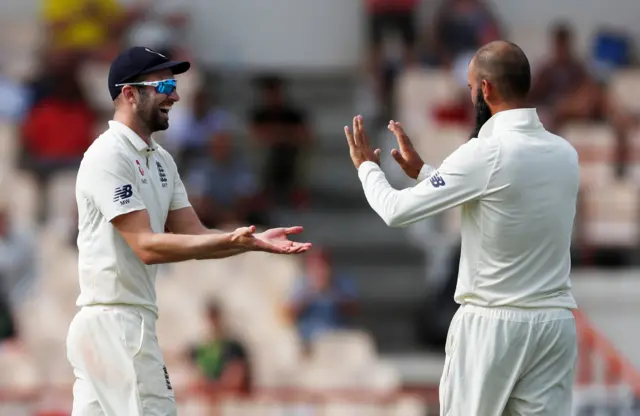 Mark Wood (L) celebrates taking a catch off the bowling of Moeen Ali