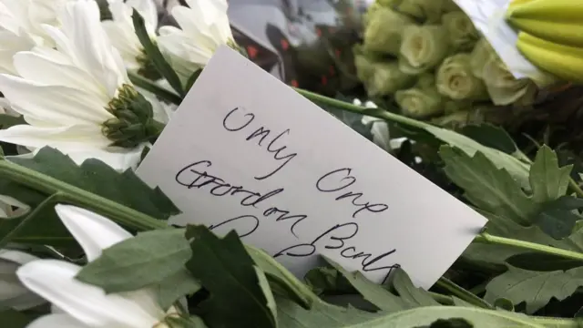 A card on one of the floral tributes