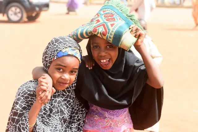 two girls carrying a prayer mat as they walk to the central mosque in northern Daura town in Katsina state ahead of Saturday's election.