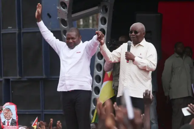 Armando Guebuza (R) and Felipe Nyussi (L) greet party supporters at a rally on 31 August 2014 in Nampula