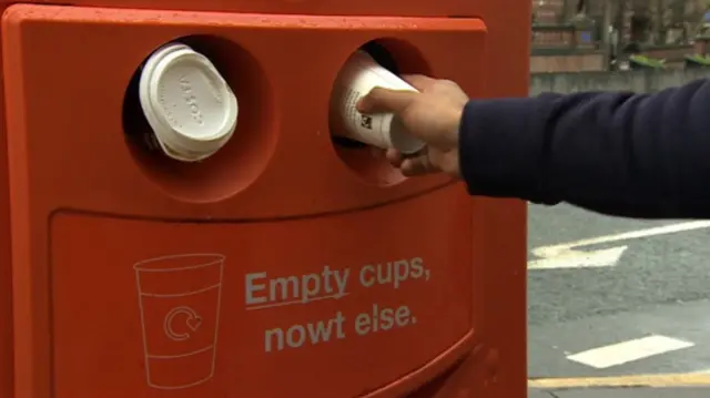 A coffee being put in a bin