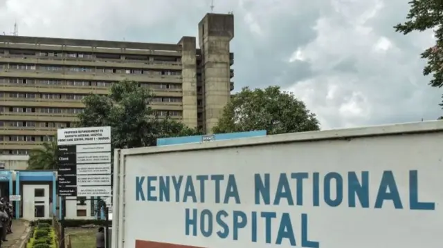 A sign reading 'Kenyatta National Hospital' stands in front of the hospital building