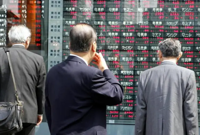 Men look at stock boards in Japan