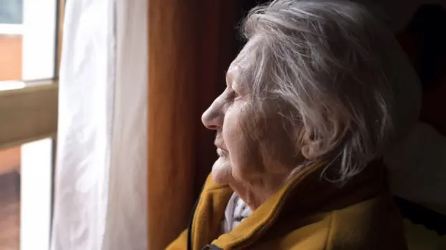 Elderly woman staring out of window