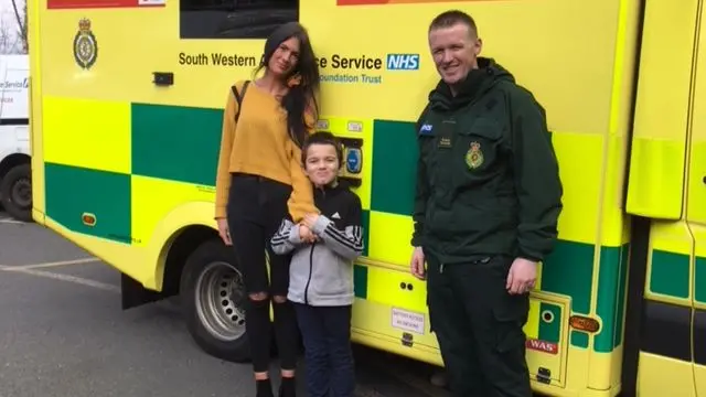 Rescued boy with mother and paramedic, by ambulance