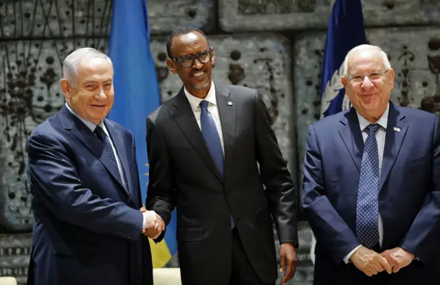 Israeli PM Benjamin Netanyahu shakes hands with Rwandan President Paul Kagame whilst Israeli President Reuven Rivlin stands next to them