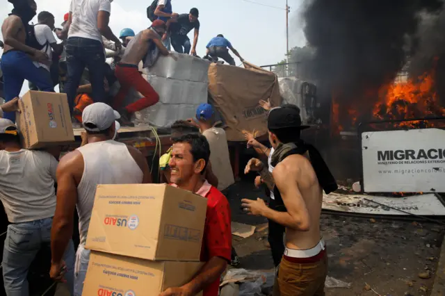 Boxes of aid are removed from a burning truck at the Venezuelan border