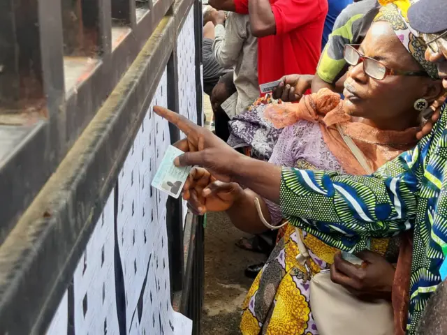 People looking at a list on a wall