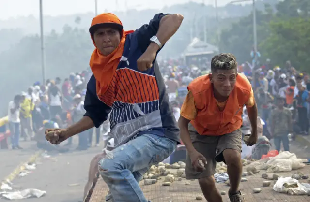 Demonstrators throw stones at the Venezuelan security forces on a bridge linking Cucuta, Colombia, and Ureña, Venezuela