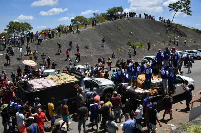 People cheer as trucks with humanitarian aid to Venezuela approach the Brazil-Venezuela border in Pacaraima, Roraima state