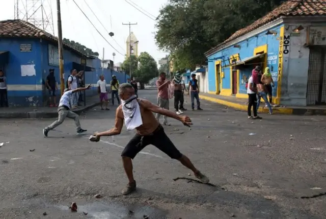 A protester throws rocks at Venezuelan security forces