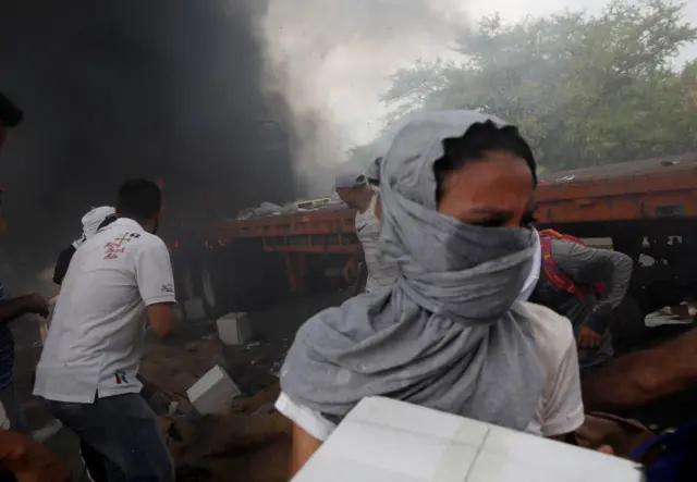 People remove aid from a burning truck at Francisco de Paula Santander bridge