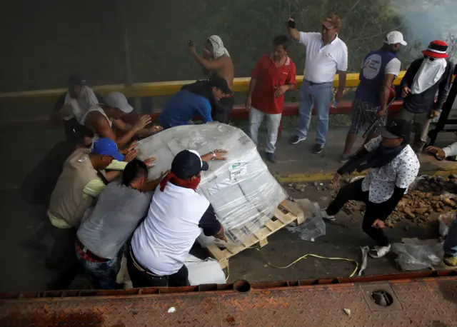 People try to save pallets of supplies from a burning truck