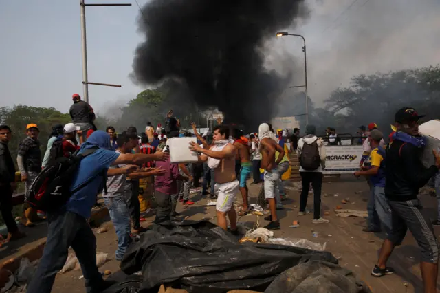 People unload humanitarian aid from a truck that caught fire on the Venezuela-Colombia border