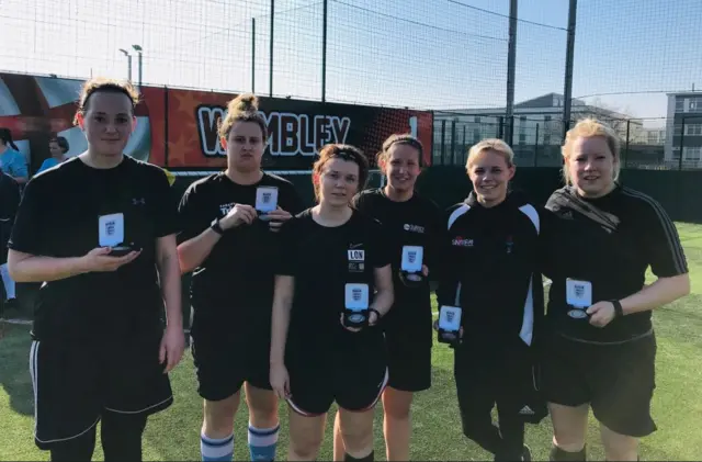 A FA People's Cup Female Walking football team standing in a line holding their runners up medals