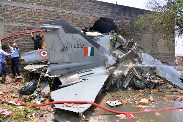 - Officials gather around the remains of an Indian Air Force Mig 27 fighter jet that crashed into a residential building in Jodhpur in India's western Rajasthan state on 13 June 2016