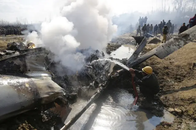 A fire fighter douses the wreckage of an aircraft after it crashed in Indian-administered Kashmir's Budgam district,