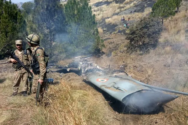 Pakistani soldiers stand next to what Pakistan says is the wreckage of an Indian fighter jet shot down in Pakistan controled Kashmir at Somani area in Bhimbar district near the Line of Control on February 27, 2019.