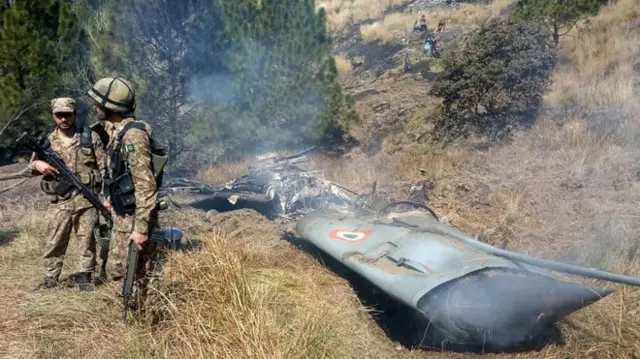 Pakistani soldiers by what Pakistan says is wreckage from a downed Indian jet