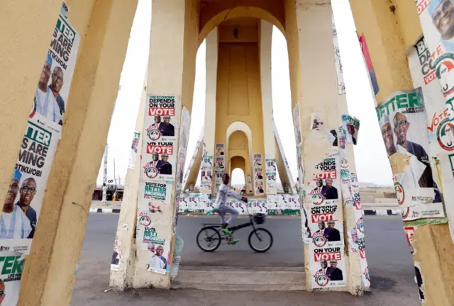 A boy rides a bicycle past a monument decorated with election posters depicting Nigeria"s main opposition party presidential candidate Atiku Abubakar with his running mate, Peter Obi, in Yola, Adamawa State, Nigeria February 26, 2019.