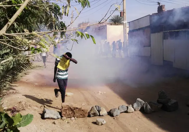 A Sudanese protester covers his face from tear gas during an anti-government demonstration