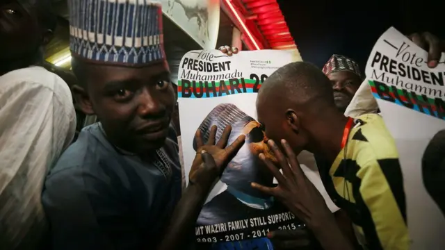 Person kissing picture of Nigerian president