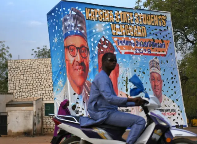 A man rides a motorbike past a billboard depicting Nigeria's President Muhammadu Buhari in Katsina, Nigeria February 27, 2019