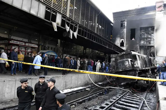 Fire fighters and onlookers gather at the scene of a fiery train crash at the Egyptian capital Cairo"s main railway station on February 27, 2019.