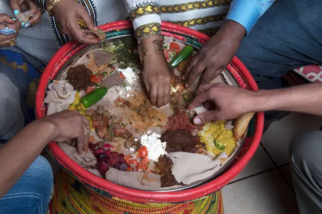 People eat injera, a popular Ethiopian food, from a communal plate.