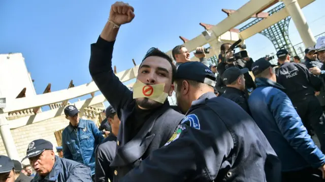 An Algerian policeman restrains a protester at the demonstration in Algiers on 28 February 2019.